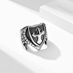Vintage steel cross shield ring with retro textured details on a white pedestal