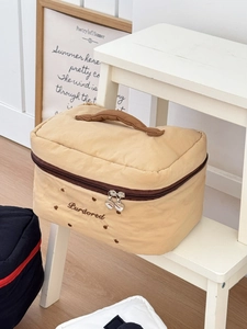 Détail de la trousse de maquillage beige matelassée avec fermetures éclair coeur et broderie