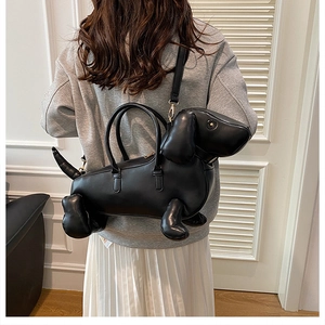 Detail view of the black dachshund-shaped leather bag size on a female model