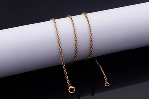 Close-up of golden stainless steel cross chain with lobster clasp on a minimalist display
