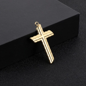 Polished gold stainless steel cross pendant with textured twill design on black background