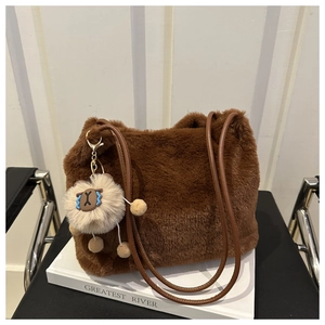Detailed texture of brown faux fur tote bag with plush charm on a minimal chair