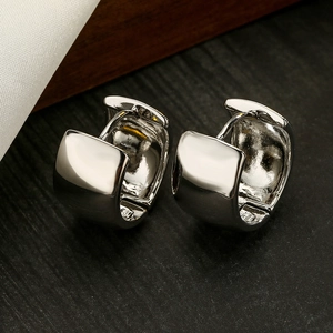 Minimalist wide silver hoop earrings with high polish finish on dark wood background