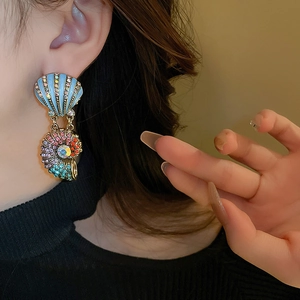 Detail of vintage gold shell earrings with colored rhinestones on a female model