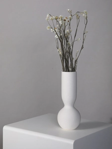 Detailed close-up of a white ceramic vase featuring minimalist horizontal ribbed texture