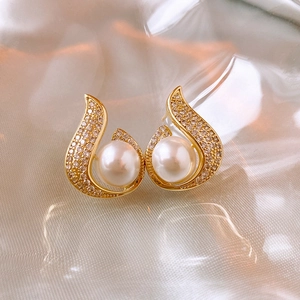 Detailed view of gold fishtail earrings with mermaid pearl and pave zircon accents