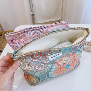 Detail of Chinese style jacquard cosmetic bag showing internal storage and golden floral patterns