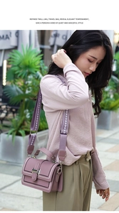 Detail of purple crossbody bag with patterned wide strap in a street style setting