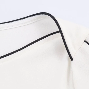 Detailopname van zwarte contrastbiezen op de halslijn en schouder van een blouse