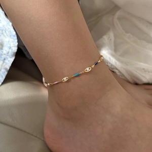 Fashionable gold anklet with colorful enamel hearts and small pearls on an ankle