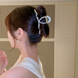 Détail d'une pince à cheveux argentée ondulée avec perles sur une coiffure relevée