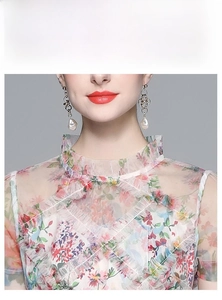 Détail du col montant à volants et imprimé fleuri sur la robe en tulle transparent