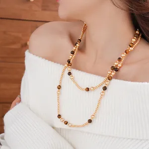 Double-layered tiger eye and gold bead long necklace worn on white knit sweater