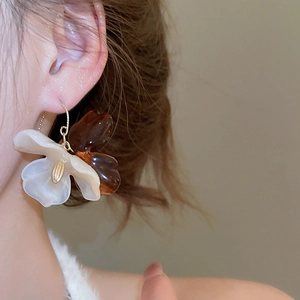Close-up of amber acrylic flower earring with gold hoop on model showing petal details