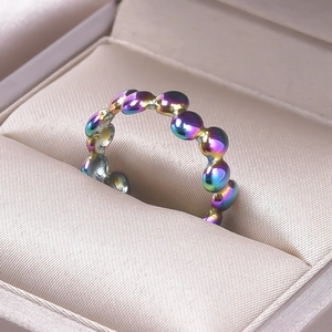 Macro detail of rainbow plated stainless steel beaded ring on luxury satin texture