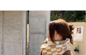 Detail of khaki and white checkered knit scarf styled as a warm winter shawl wrap