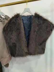 Detailed close-up of dark brown faux fur vest with plush texture on a gold hanger