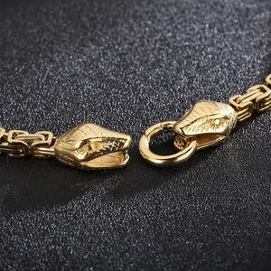 Vue macro des fermoirs tête de serpent dorés et de la chaîne en métal tressé