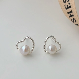Detailed view of silver heart-shaped stud earrings with centered round white pearls
