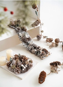 Close-up of Nordic Christmas pine cone wreath and garland with snowy rustic details
