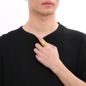 Detail of a men's gold punk skull ring with horn accents worn by a model on a white background
