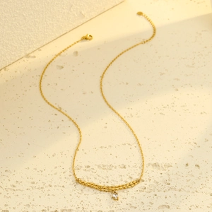 Elegant gold double-layered necklace with an oval crystal pendant on a matte background