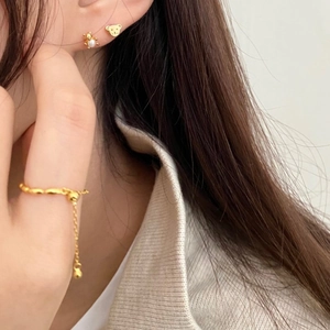 Detail of adjustable gold ring with small pendant and bear earrings with pearls