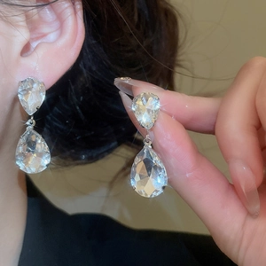 Macro detail of silver-tone teardrop pendant earrings with sparkling faceted crystals