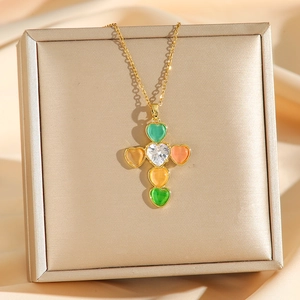 Golden cross necklace with colorful heart-shaped zircons on premium silk background