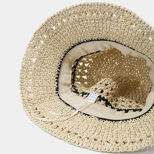 Detailed close-up of 100% paper material and adjustable sweatband inside the beige straw hat