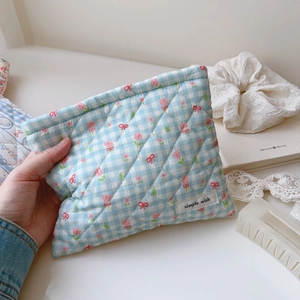 Pochette matelassée en coton à carreaux bleus et tulipes tenue à la main