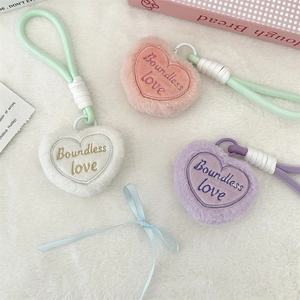 Close-up of heart-shaped plush keychains with Boundless Love embroidery in pink, white and purple