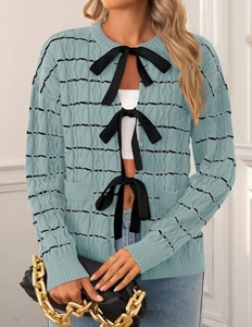 Detailed knit texture of light blue cardigan with black stripes and ribbon bow closures