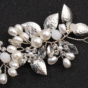 Close-up of bridal headpiece featuring white pearls, crystals and silver metal leaves