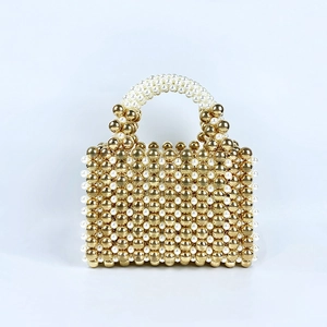 Detailed view of hand-woven golden beads and white pearls on a luxury evening handbag