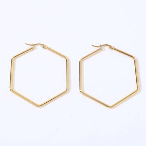 Macro view of gold stainless steel hexagonal geometric hoop earrings on white background