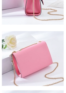 Detail of pink Saffiano cross-pattern leather handbag with golden chain strap on white background