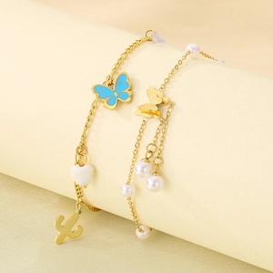 Detail of 18k gold butterfly anklets with blue charm and white pearls on a soft base