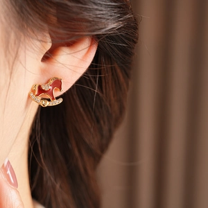 Dettaglio orecchino a cavallo a dondolo con smalto rosso e zirconi su modella