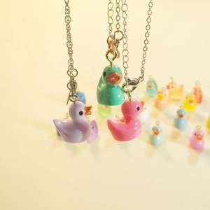 Handmade colorful resin duck pendants on silver chains in purple, green, and pink
