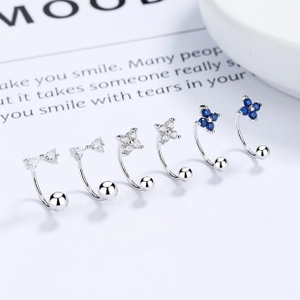 Macro detail of 925 sterling silver butterfly and clover earrings with screw backs