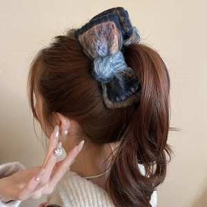 Macro shot of large multi-color knitted bow hair clip on a model's ponytail