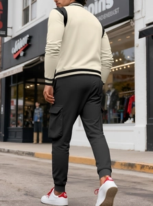 Vista posteriore della giacca da baseball beige da uomo e pantaloni cargo neri stile street