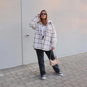 Détail d'une surchemise à carreaux épaisse avec un sweat à capuche blanc et sac beige