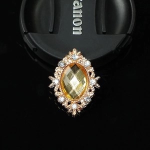 Macro detail of oval yellow crystal alloy charm with sparkling white rhinestones