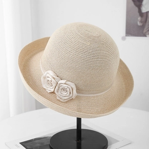 Détails de la texture en paille tressée et des deux fleurs faites à la main sur le chapeau
