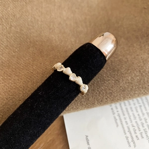 Détail d'une bague coeur en émail crème avec zircons sur un anneau doré à l'or