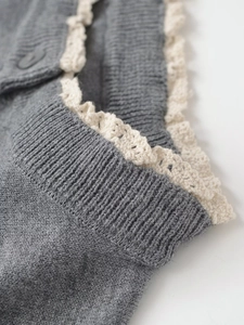 Close-up of grey knit cardigan featuring delicate off-white lace trim and ribbed textures