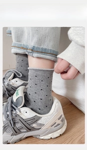 Detailed side view of grey polka dot cotton socks with rolled edge and casual sneakers