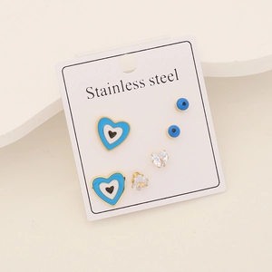 Detail of three pairs of stainless steel earrings with evil eye and blue heart studs